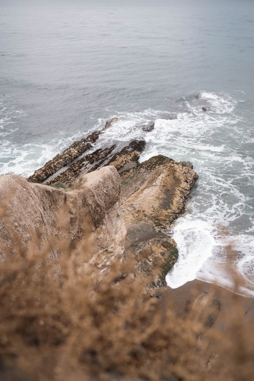 Dramatic ocean waves crashing against rocky coastline at sunset on California's central coast.