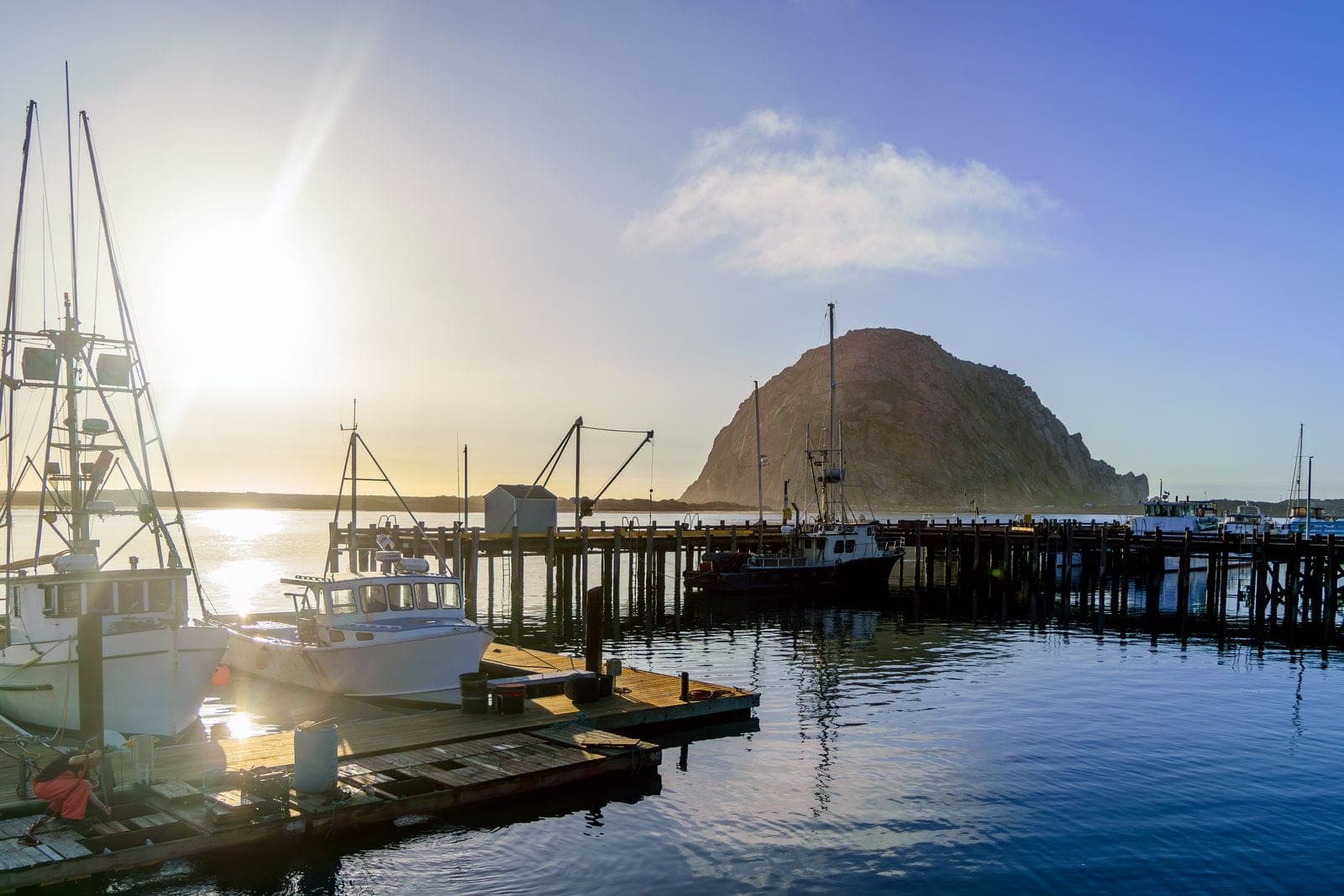 Morro Bay harbor with boats and Morro Rock at sunset